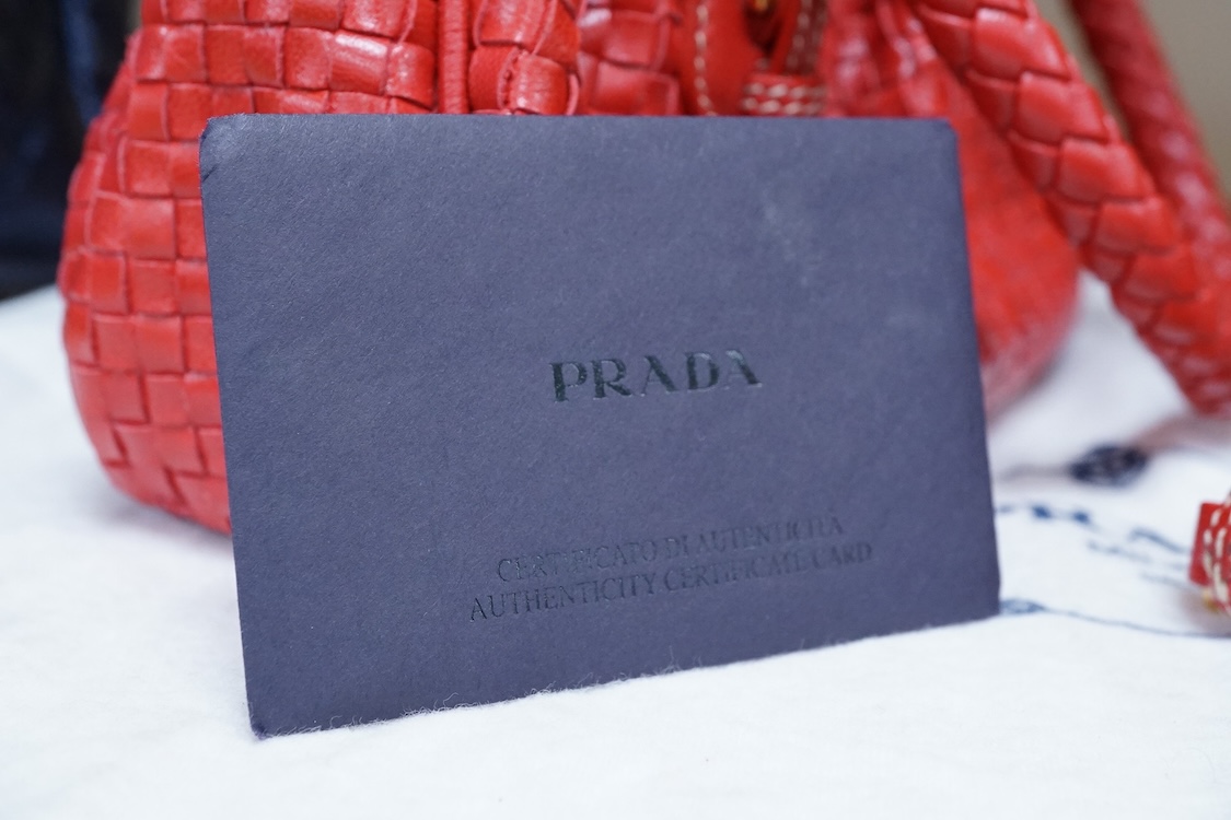 A Prada red braided leather handbag with shoulder strap, authenticity card and dust cover, 25cm wide, Provenance: Purchased by the vendor in Selfridges